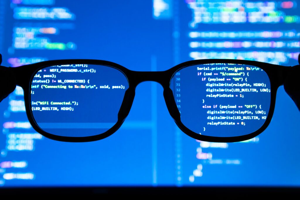 A pair of glasses in front of a screen with binary code.